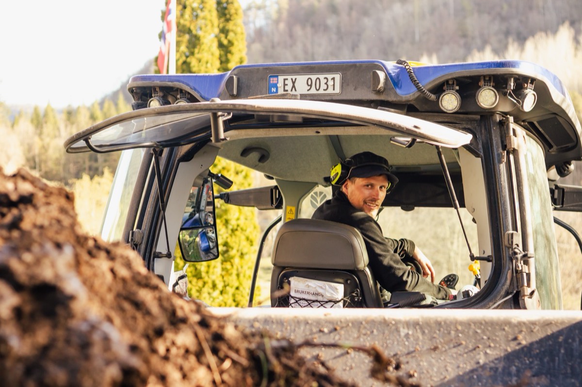 Roy Erik Hansen i LH Drift i førerhuset på en New Holland-traktor.